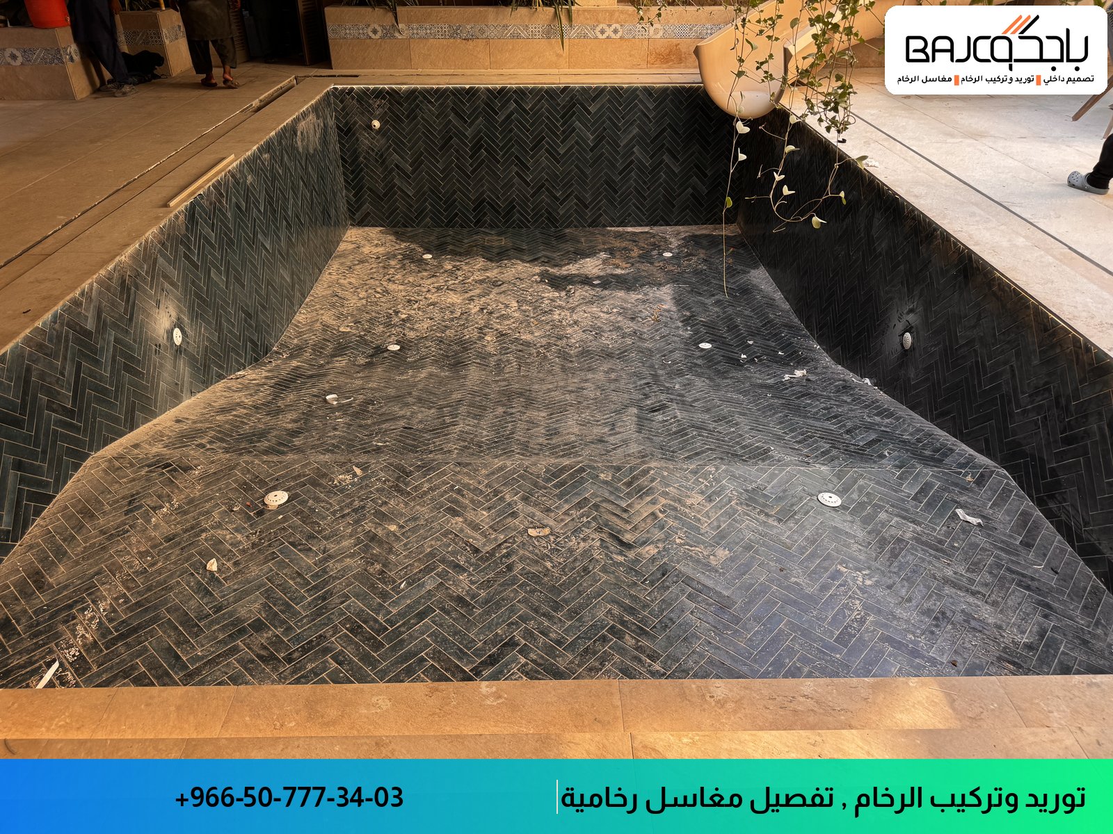 حوض سباحة بأرضية رخام أسود بنمط هندسي متقاطع، مع جدران مماثلة ومخرج مياه علوي