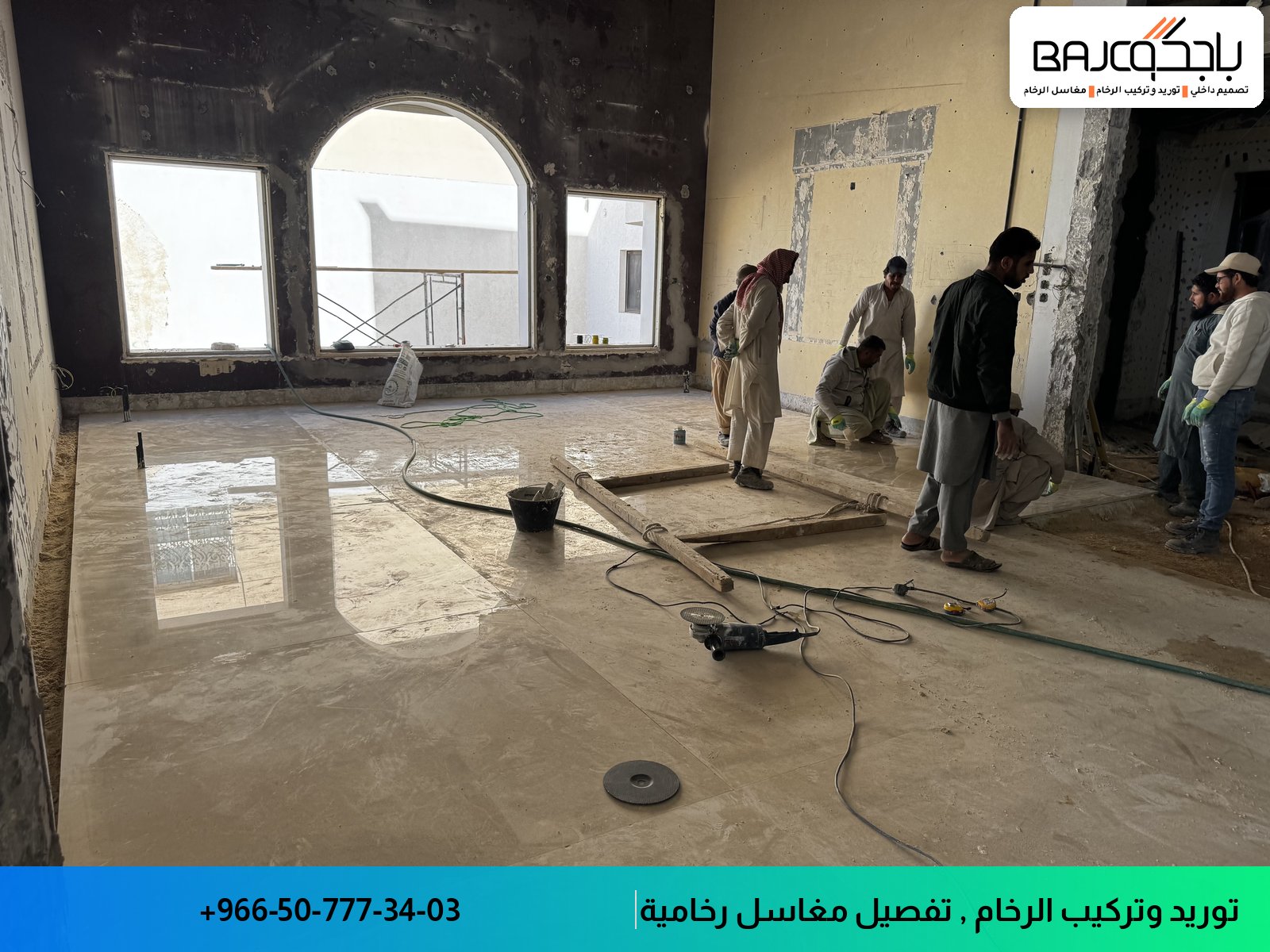 فريق عمل يقوم بتركيب أرضيات رخام في مساحة داخلية واسعة مع نوافذ كبيرة، والأرضية لم تكتمل بعد