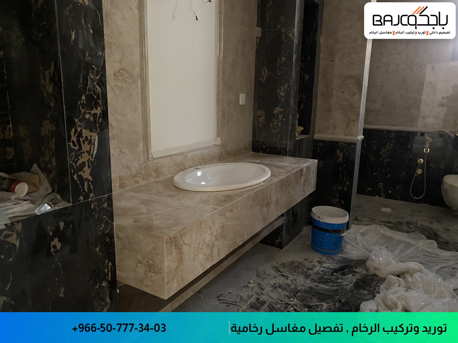 مغسلة رخام بيج بحوض واحد مثبتة على جدران من الرخام الأسود مع مرآة معلقة في حمام تحت الإنشاء