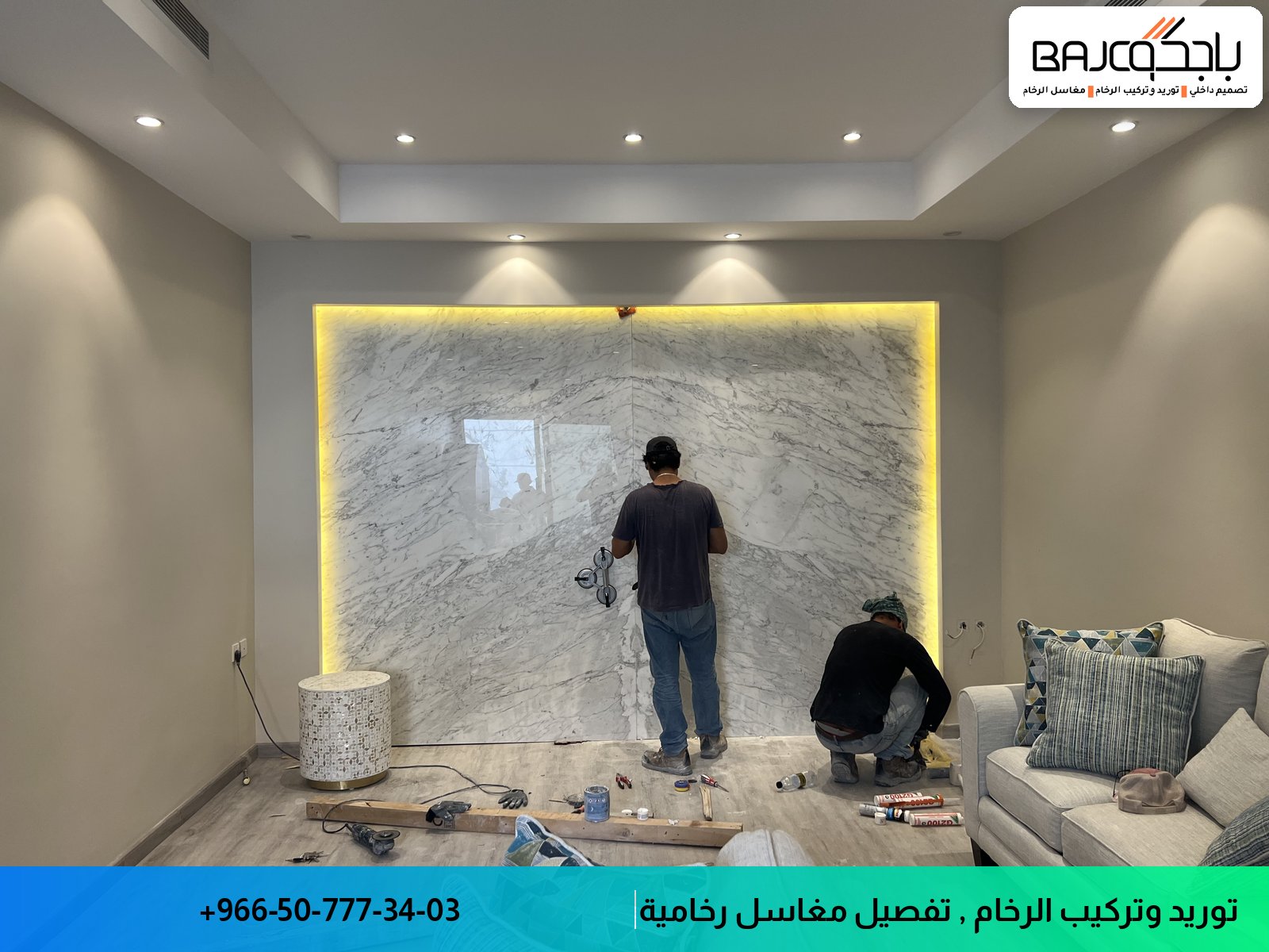 عامل يقوم بتركيب جدارية رخامية بيضاء اللون بعروق رمادية مع إضاءة صفراء في جدار غرفة حديثة