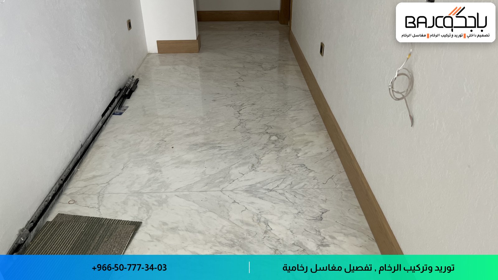 ممر بأرضية رخام أبيض بعروق رمادية، مع جدران بيضاء وسقف مشطوب، وكابل كهربائي على الجدار الأيمن