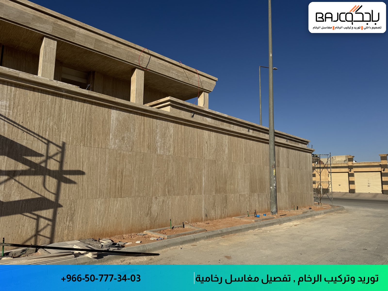 واجهة خارجية مغطاة برخام بيج فاتح بعروق دقيقة، مع أعمدة خرسانية وسياج معدني