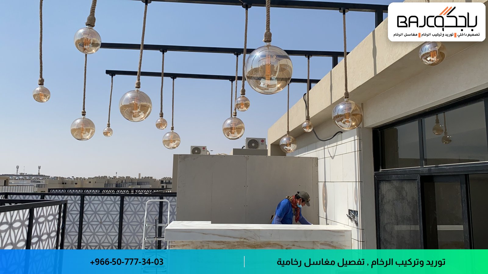 مغسلة رخام أبيض مثبتة على شرفة حديثة مع إضاءة معلقة وإطلالة على المدينة