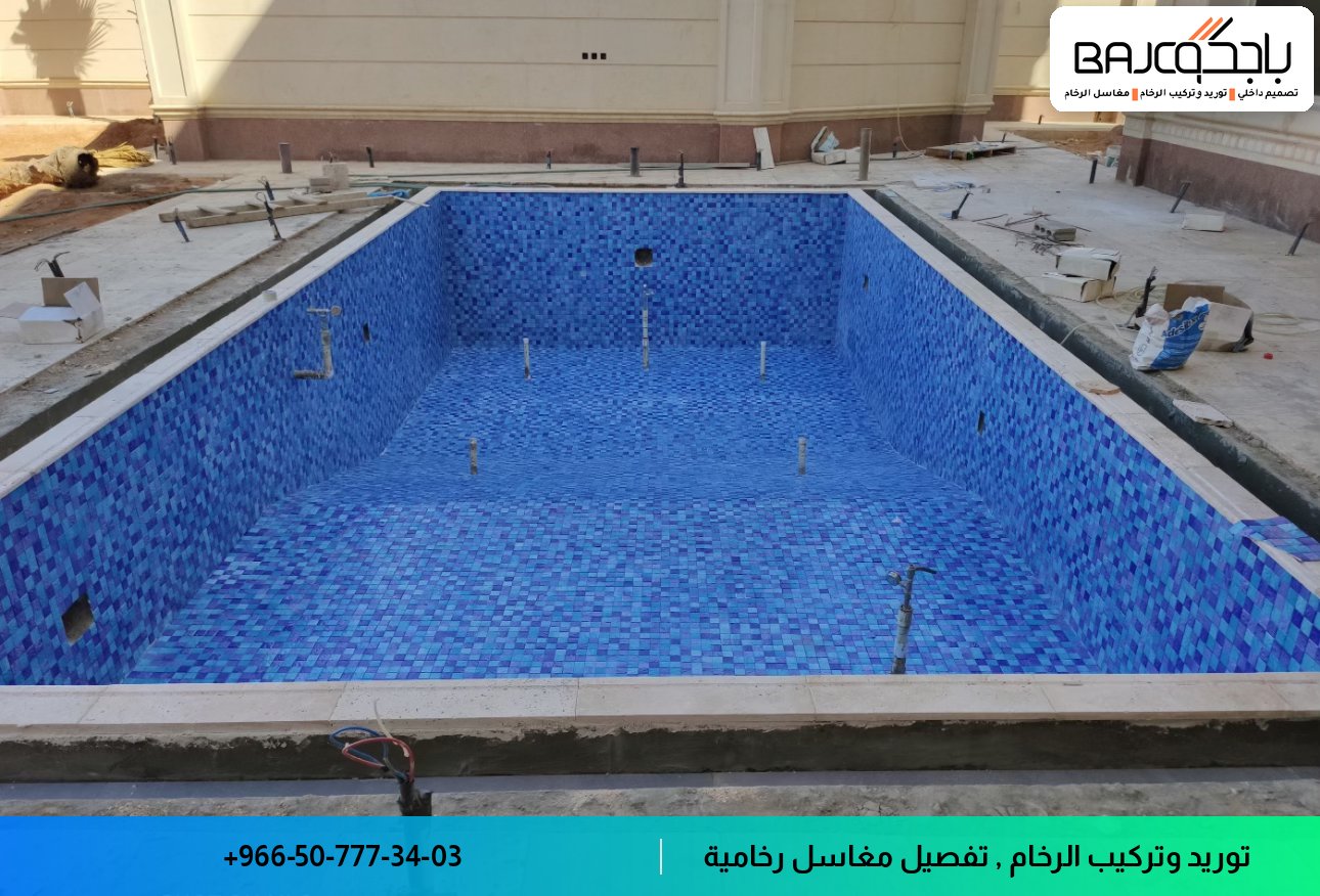 حمام تحت الإنشاء برخام أزرق موزايكو على الأرضية وحوض سباحة كبير محاط بإطار رخام